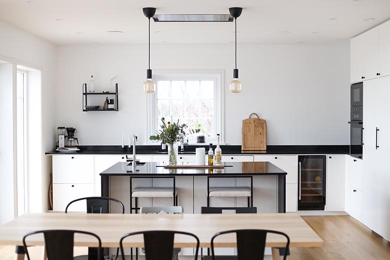 I köket går färgerna i svart och vitt med en stilren inbyggnadsfläkt i taket som går att styra via Google Home.