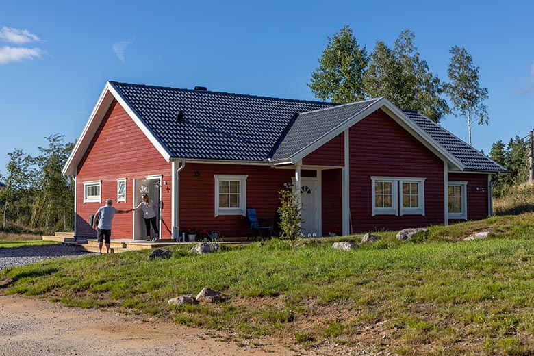 Två personer skakar hand framför ett rött hus