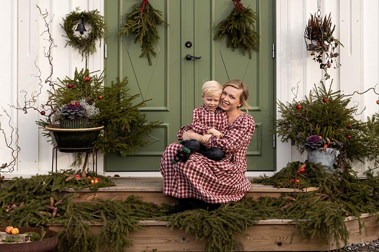 Mor och son framför dörr till vitt hus