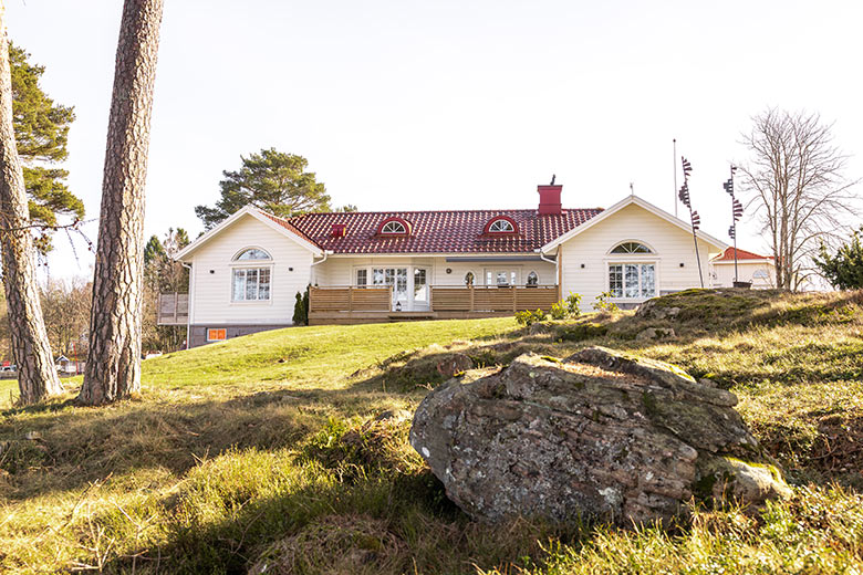 Hus i form av ett H. Uppe på en kulle vid sjön Mjörn.