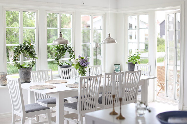 Köksbord och stolar i vitt. Ljus veranda i skärgårdsstil.