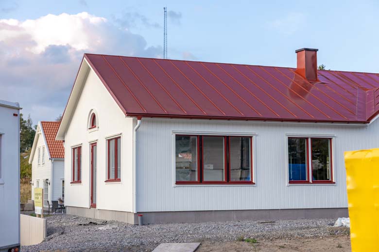 Vitt hus med rött plåttak. Baksida