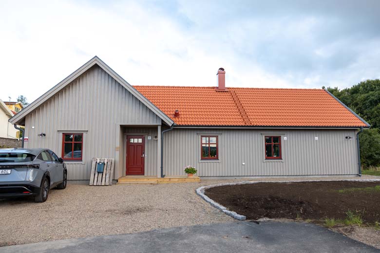 Grått hus med oranget tak och röd dörr