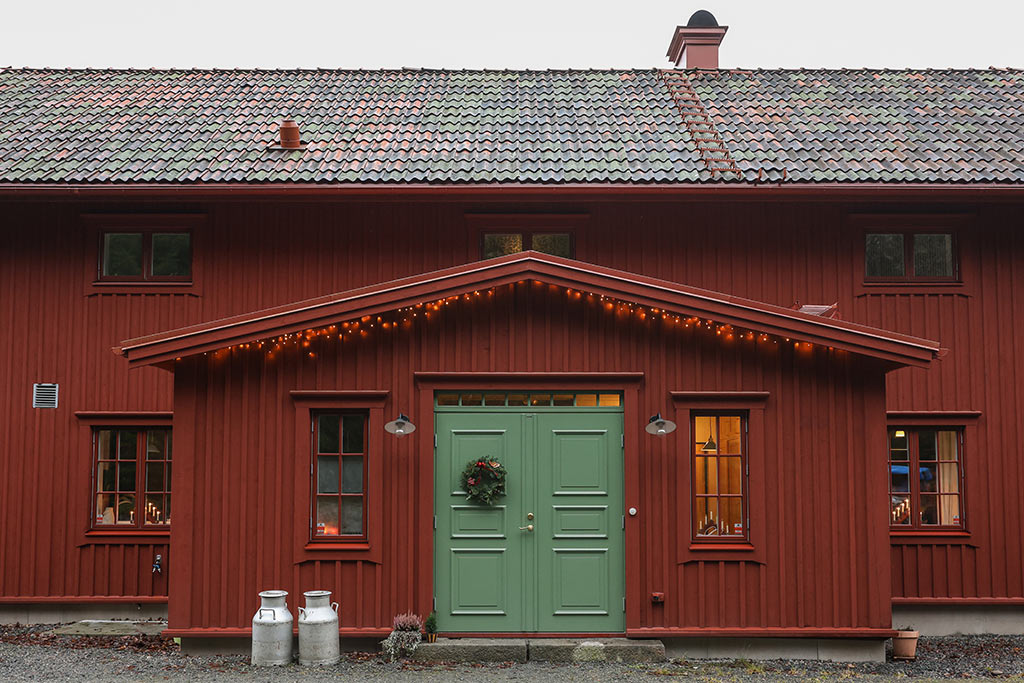 Huset framifrån. Rött hus med grön ytterdörr.