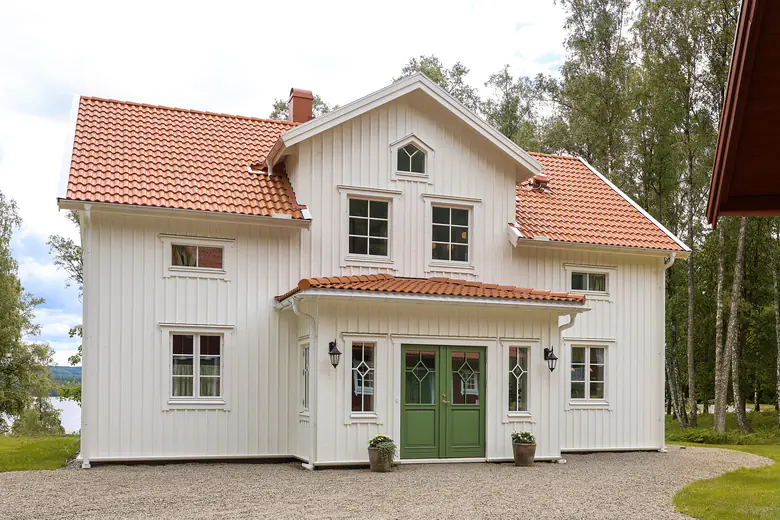 Trähus i lösvirke med grön dörr.